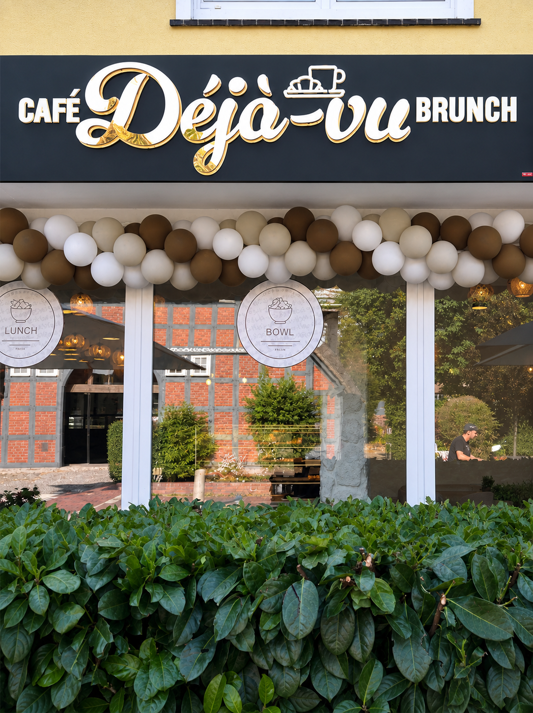 Vollständige Außenansicht des Café déjà vu mit Schild, Ballons und Sitzbereich